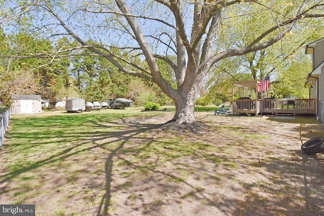 view of yard with a wooden deck and a storage shed