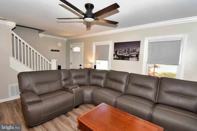 living room featuring visible vents, crown molding, wood finished floors, and ceiling fan