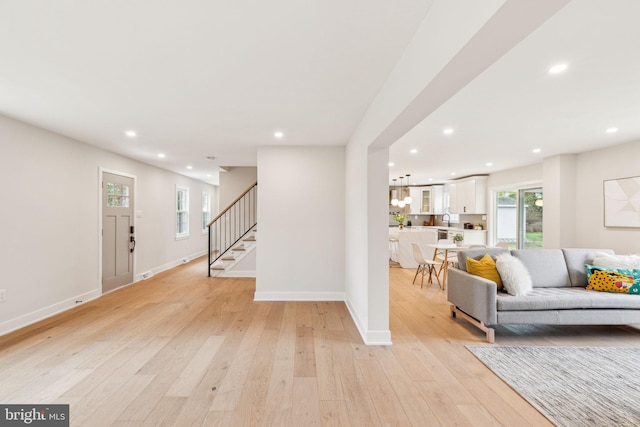 living room featuring baseboards, recessed lighting, stairs, and light wood-type flooring