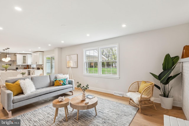living room with light wood-type flooring, baseboards, visible vents, and recessed lighting
