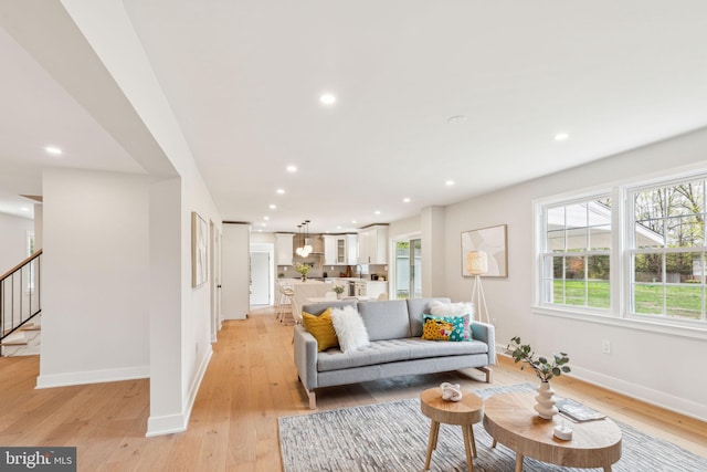 living area featuring recessed lighting, stairs, light wood finished floors, and baseboards