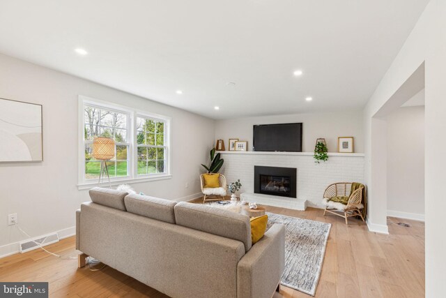 living area with recessed lighting, visible vents, baseboards, a fireplace, and light wood-style flooring