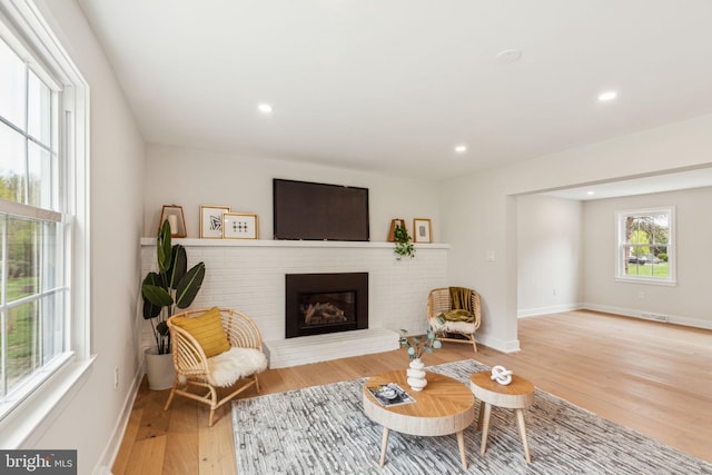 living room with a fireplace, light wood-type flooring, baseboards, and recessed lighting