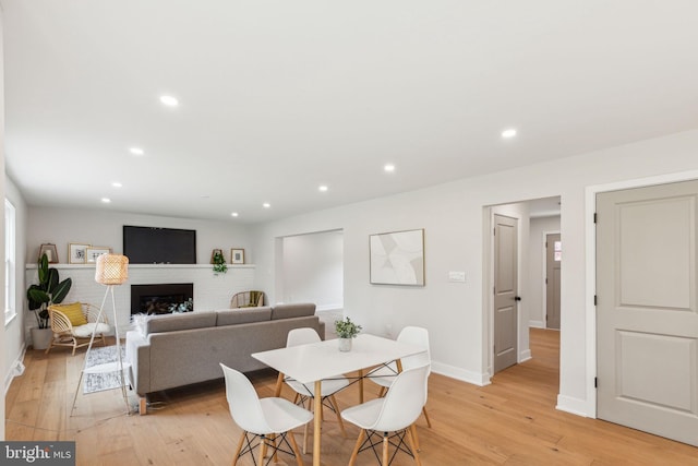 dining area featuring light wood-type flooring, baseboards, a fireplace, and recessed lighting