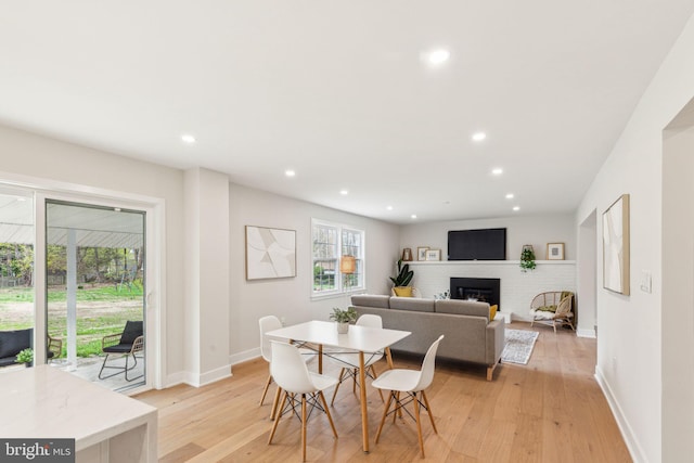 dining space with a fireplace, light wood-type flooring, baseboards, and recessed lighting