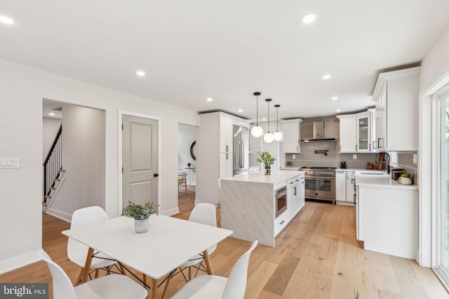 kitchen featuring a sink, light countertops, white cabinets, high end stainless steel range oven, and a kitchen island