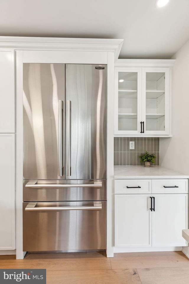 interior space featuring light countertops, glass insert cabinets, white cabinetry, and high end refrigerator