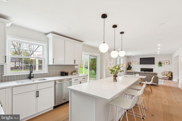 kitchen with dishwasher, light countertops, a sink, and backsplash