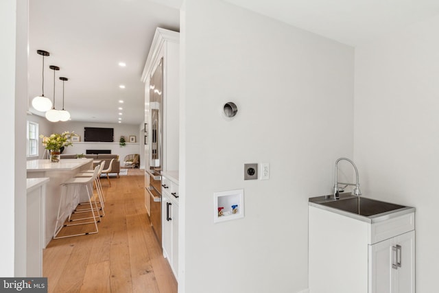 laundry room with recessed lighting, laundry area, a sink, light wood-type flooring, and washer hookup