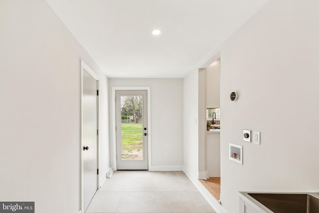doorway to outside featuring baseboards, light tile patterned flooring, a sink, and recessed lighting