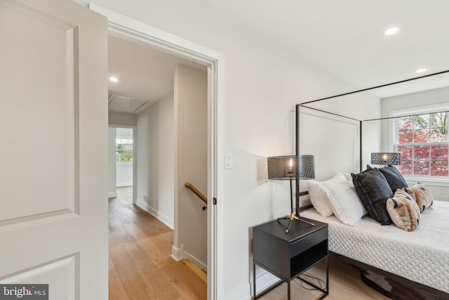bedroom featuring attic access, baseboards, recessed lighting, and light wood-style flooring