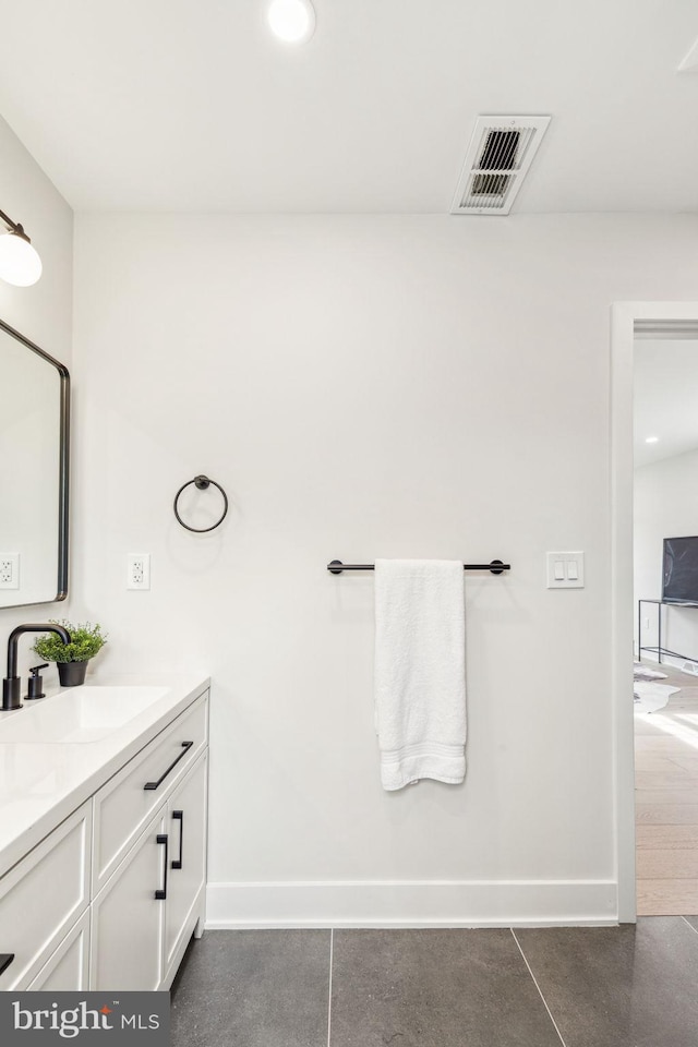 bathroom with double vanity, visible vents, baseboards, and a sink