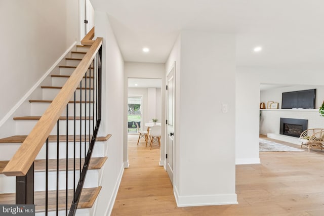 hall with baseboards, stairs, light wood-type flooring, and recessed lighting