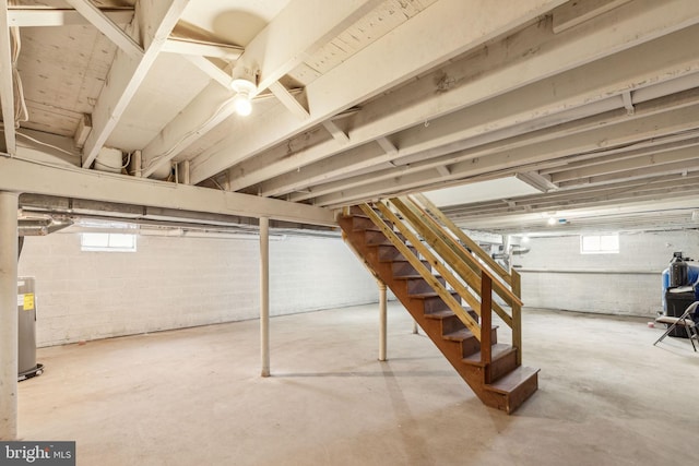below grade area featuring plenty of natural light, water heater, and stairs