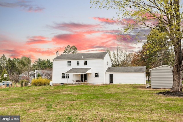 back of house at dusk featuring a storage shed, a lawn, crawl space, and an outdoor structure
