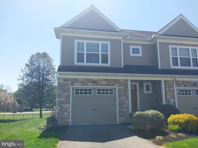 craftsman inspired home featuring driveway, stone siding, an attached garage, and fence