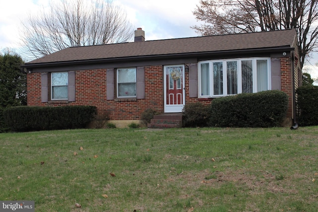 ranch-style home with a front yard, brick siding, entry steps, and a chimney