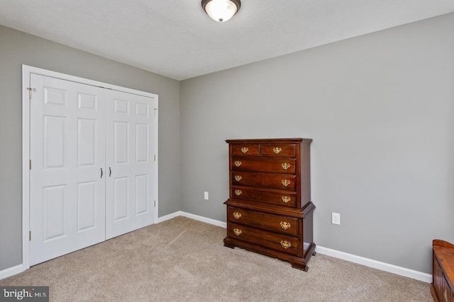 carpeted bedroom with a closet and baseboards