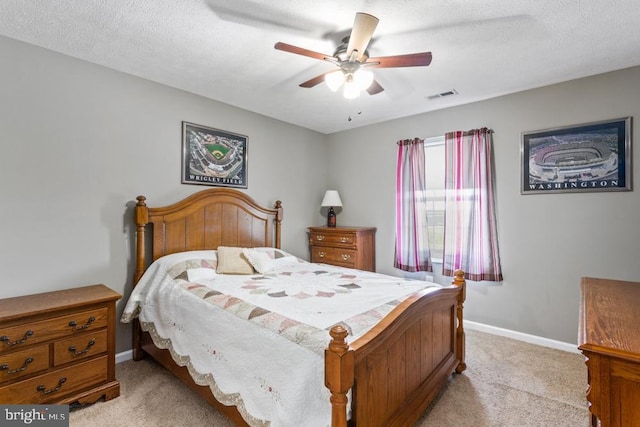bedroom featuring baseboards, light carpet, a textured ceiling, visible vents, and ceiling fan