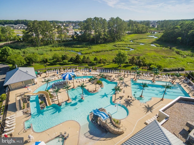 community pool featuring fence, a patio, and view of scattered trees