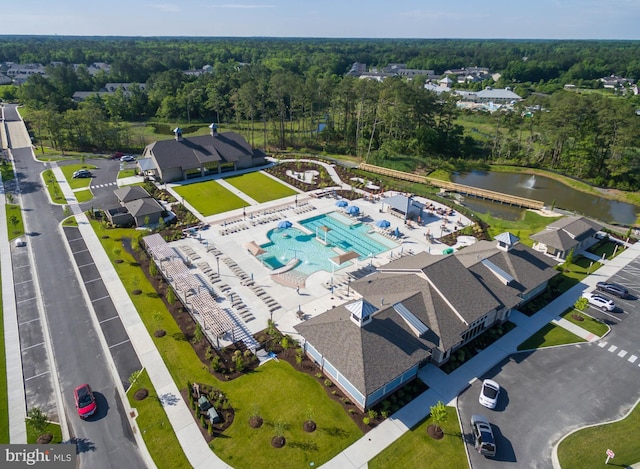 drone / aerial view of a large body of water, a pool, and a heavily wooded area