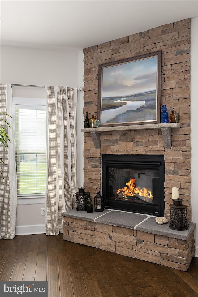 detailed view of a stone fireplace, wood finished floors, and baseboards