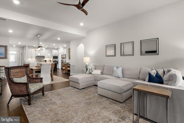 living room featuring arched walkways, a ceiling fan, dark wood-type flooring, and recessed lighting
