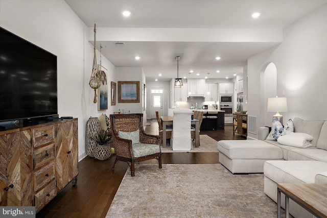 living area featuring dark wood-style flooring, arched walkways, and recessed lighting