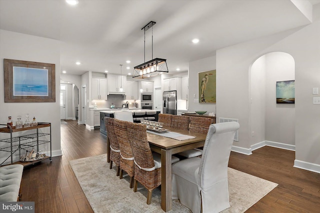 dining room featuring arched walkways, baseboards, dark wood finished floors, and recessed lighting