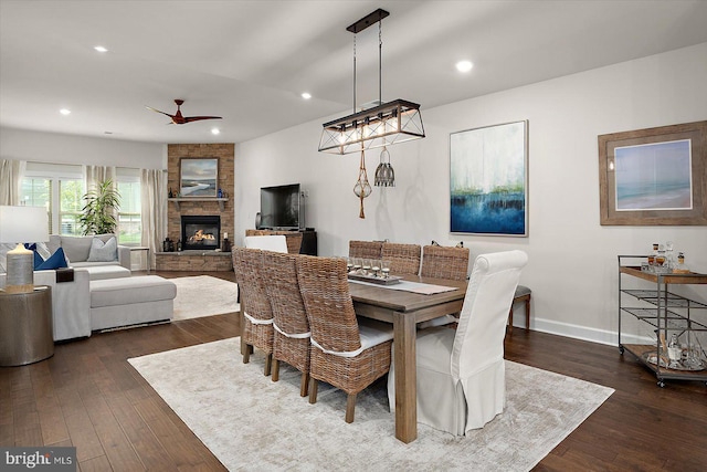 dining space featuring ceiling fan, dark wood-style flooring, a fireplace, baseboards, and recessed lighting