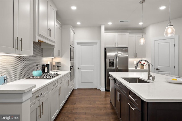 kitchen with a sink, appliances with stainless steel finishes, dark wood-style floors, backsplash, and recessed lighting