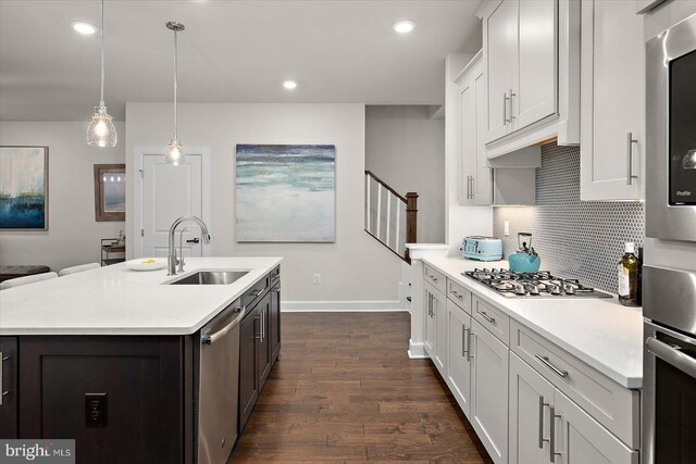 kitchen with a sink, appliances with stainless steel finishes, light countertops, baseboards, and tasteful backsplash