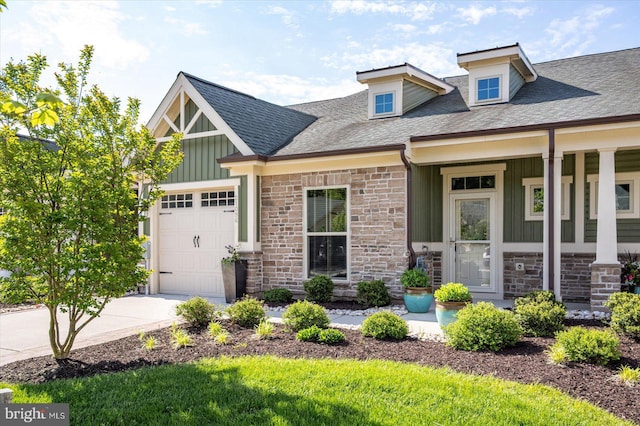craftsman house with stone siding, an attached garage, board and batten siding, and driveway