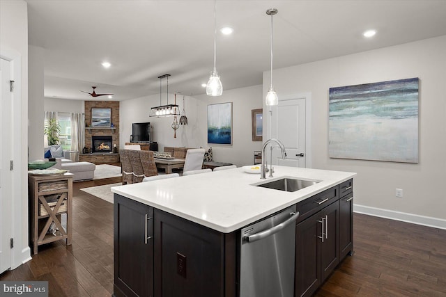 kitchen featuring a sink, dishwasher, a fireplace, dark wood finished floors, and light countertops