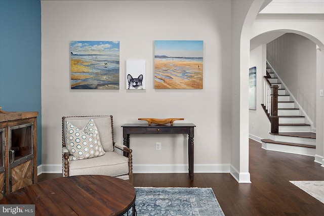living area featuring wood-type flooring, baseboards, arched walkways, and stairs