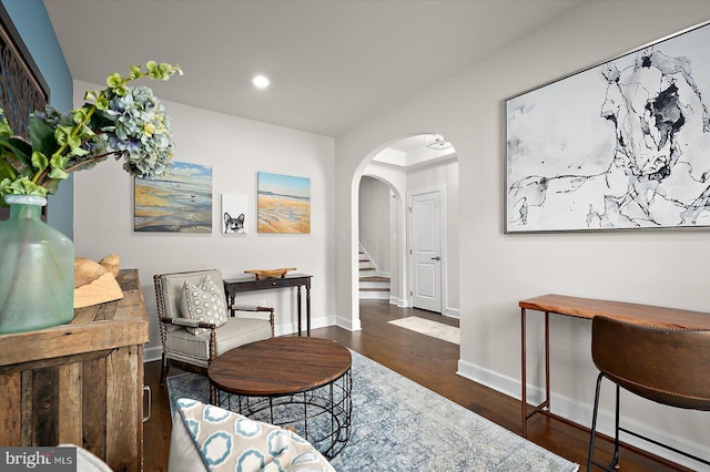 living area with arched walkways, recessed lighting, baseboards, wood finished floors, and stairway