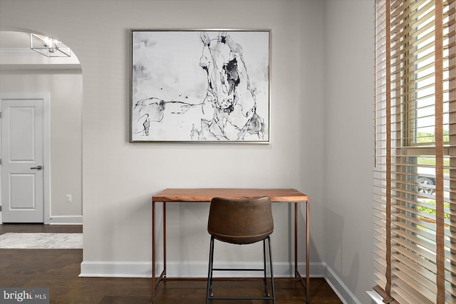 office with baseboards, arched walkways, and wood finished floors