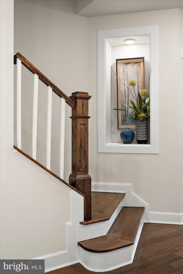 staircase featuring baseboards and wood finished floors