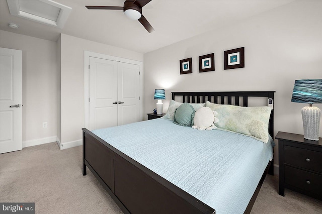 bedroom with light carpet, baseboards, attic access, a closet, and a ceiling fan