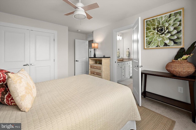 carpeted bedroom featuring a closet, ensuite bathroom, and a ceiling fan