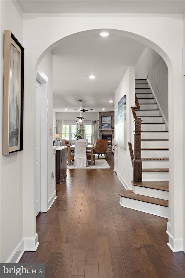entrance foyer with stairs, dark wood-style floors, a large fireplace, recessed lighting, and baseboards