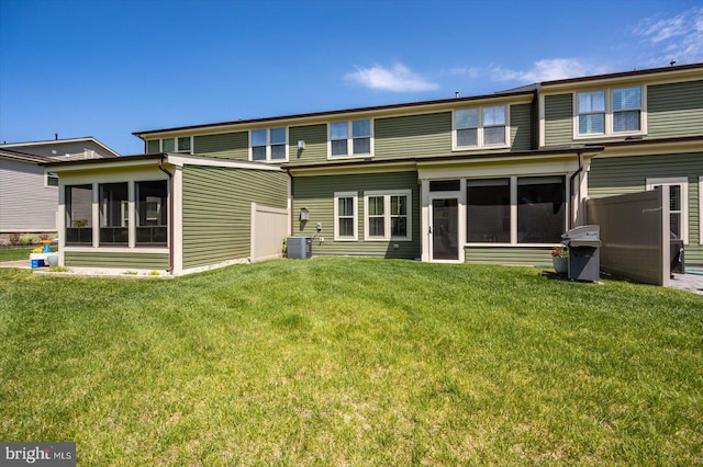 rear view of house featuring a sunroom, a lawn, and central air condition unit