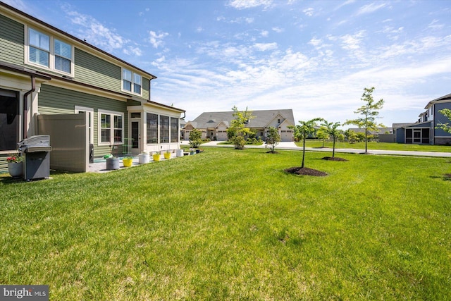 view of grassy yard with a sunroom