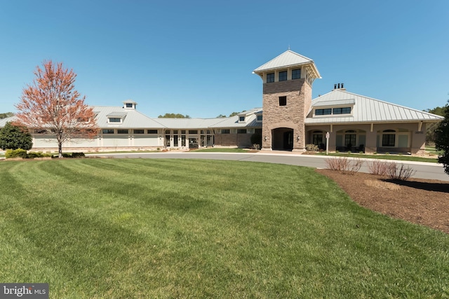 exterior space featuring a standing seam roof, metal roof, a yard, and stone siding