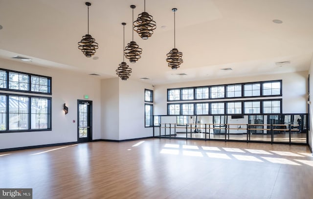 spare room featuring a high ceiling, plenty of natural light, wood finished floors, and baseboards