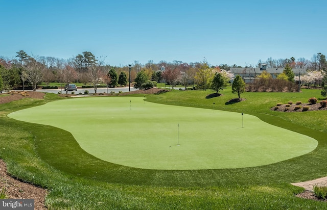 view of property's community with view of golf course, an area to practice putting, and a lawn