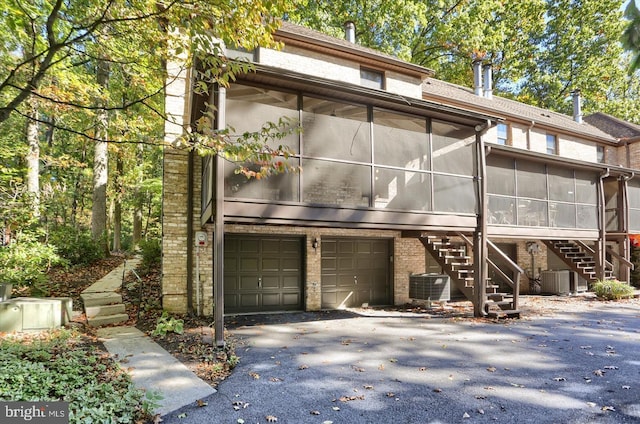 1300 Sand Hill Rd, Hummelstown, PA 17036 - view of front of house with a sunroom, cooling unit, stairway, brick siding, and a garage