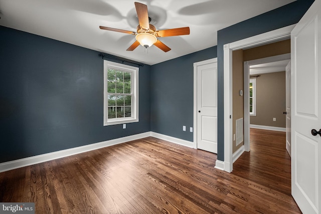 empty room featuring ceiling fan, dark wood finished floors, and baseboards