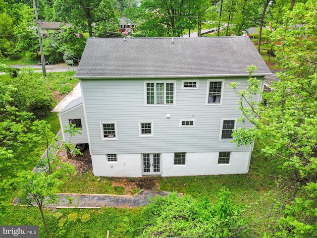 rear view of house with french doors, a shingled roof, a chimney, and view of scattered trees