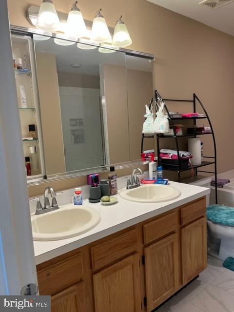302 Weston Ln Unit 23, New Hope, PA 18938 - bathroom featuring double vanity, marble look tiles, and toilet